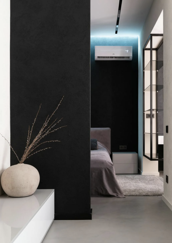 a room with a black wall and a white vase with a plant